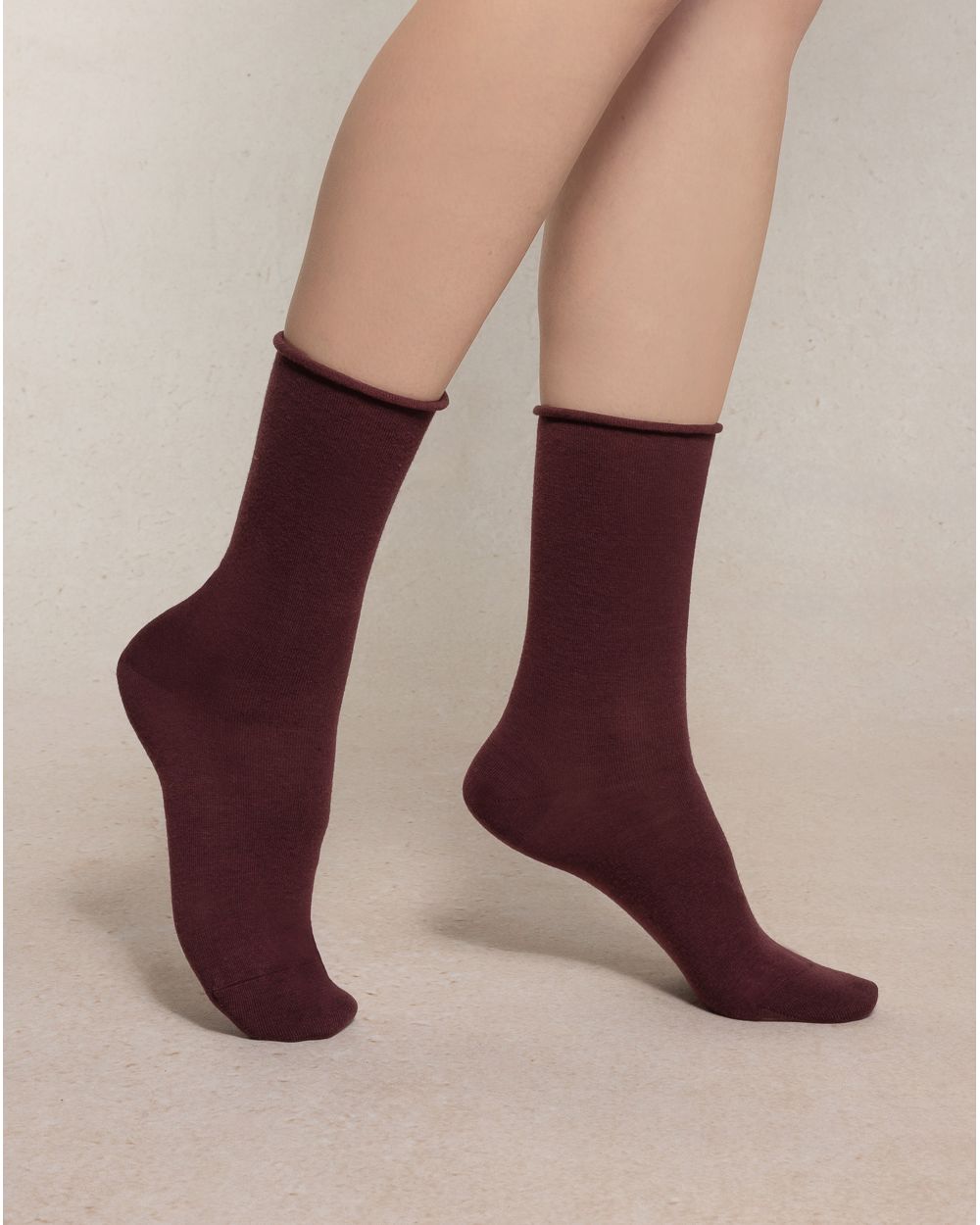 Burgundy socks worn by a person on a beige background